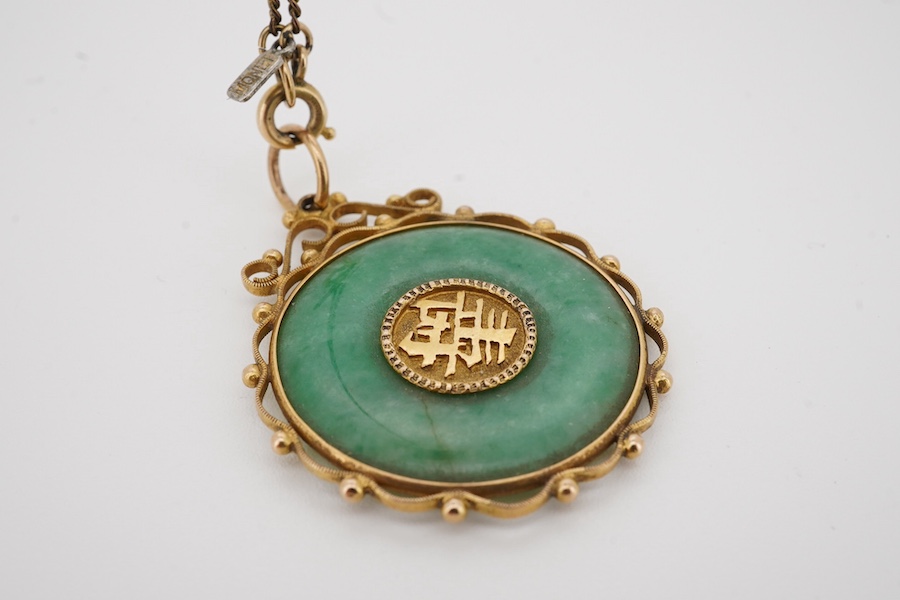 A Chinese yellow metal mounted carved jade 'Shou Fu' pendant, 36mm, on a gilt metal chain. Condition - fair to good